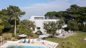 A modern two-story house with a swimming pool, outdoor seating, and a covered patio. - Villa d’exception, Vue mer et Rooftop Super Cannes (Vallauris)