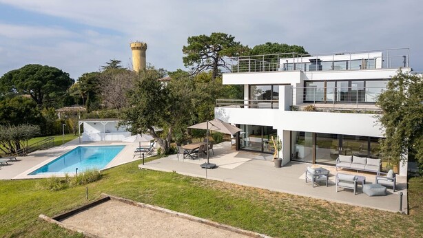 A modern two-story house with a swimming pool, outdoor seating, and a tower in the background. - Villa d’exception, Vue mer et Rooftop Super Cannes (Vallauris)