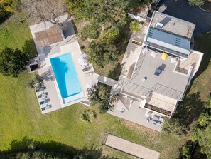 Eine Vogelperspektive eines modernen Hauses mit Swimmingpool, Terrasse und überdachtem Außenbereich.