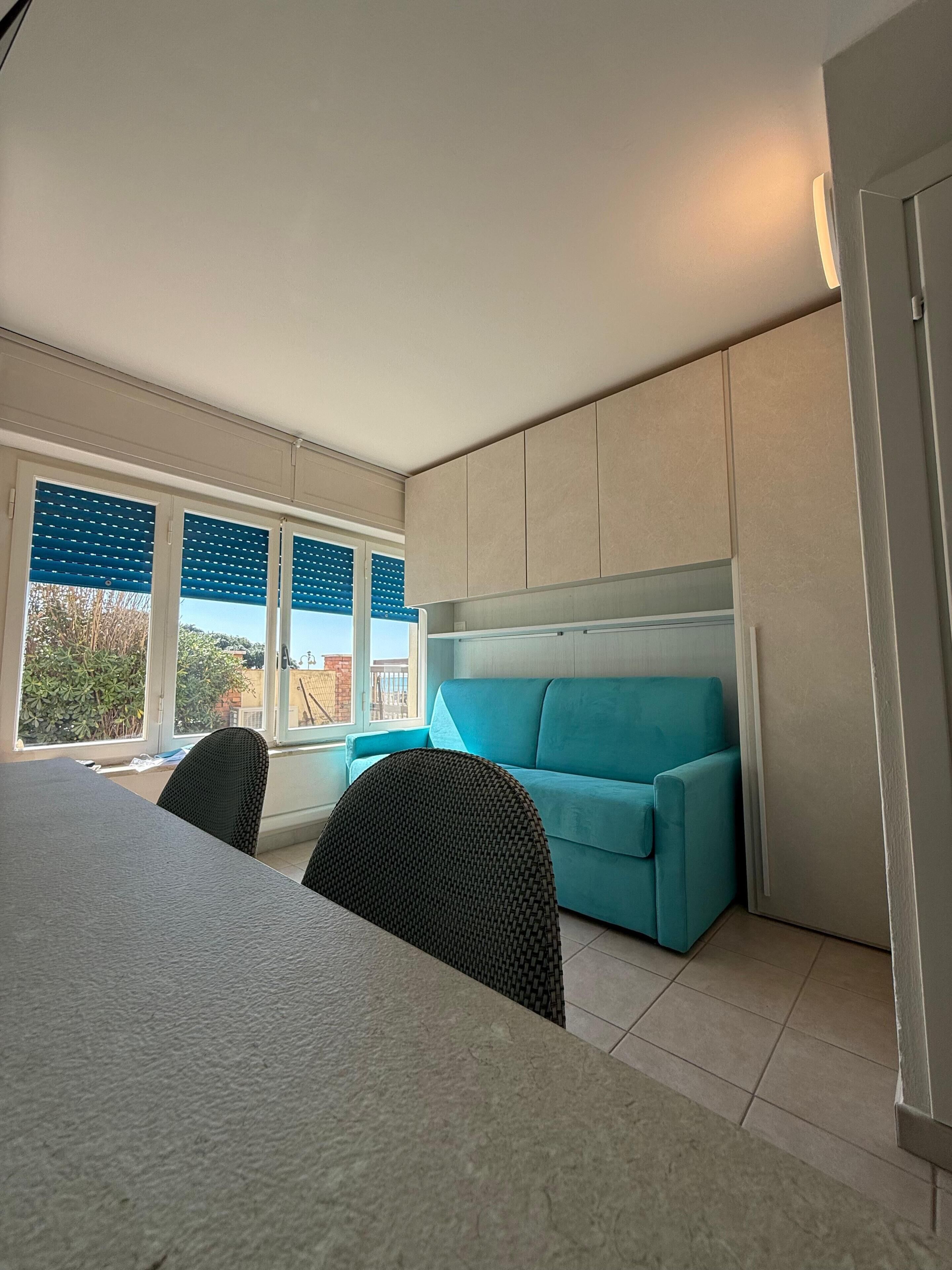 A modern room with a bed, a blue sofa, and a dining table.