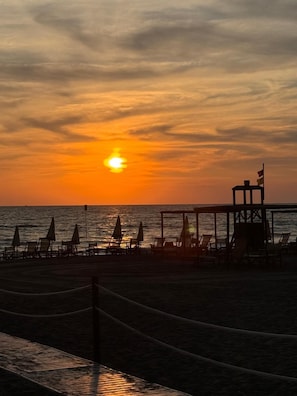 A beach scene with a wooden pier, lounge chairs, and umbrellas. - A vacation with a window to the sea!!! Studio apartment within walking distance of the beach. (Marina di Castagneto Carducci)