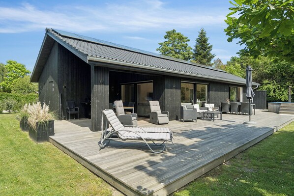 Une maison moderne dotée d’un espace extérieur couvert, comprenant une terrasse et du mobilier d’extérieur.