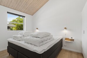 Une chambre à coucher moderne avec un lit, une fenêtre et une étagère fixée au mur.