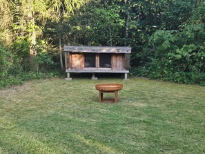 A rustic wooden structure with a bench and a table in a grassy area.