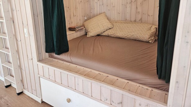 A wooden bed with a mattress and pillows, a white drawer, and a ladder. - New and modern holiday home with hot tub (Grenaa)