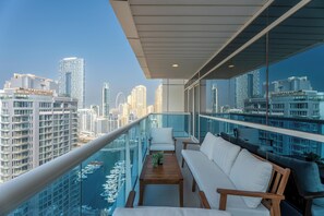 A balcony with a city view, a sofa, a table, and a railing. - Gala Guests - Classic Opal Tower Suites Dubai Marina (Dubai)