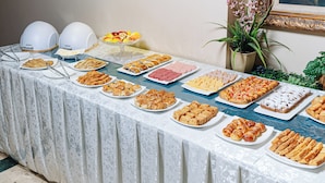 Un tavolo per buffet con diversi cibi e una pianta in vaso.