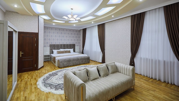 Camera da letto con un letto, un divano, un tappeto decorato e un soffitto con faretti.