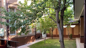 Un cortile con prato, alberi e un edificio con finestre e una porta.