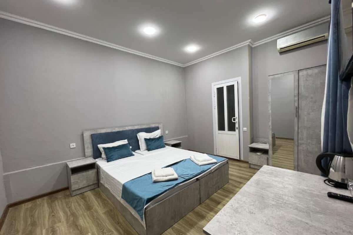 A modern bedroom with a bed, nightstands, a desk, and a wardrobe.