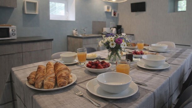 Een ontbijt met croissants, aardbeien en sinaasappelsap op een tafel met een geruit tafelkleed.