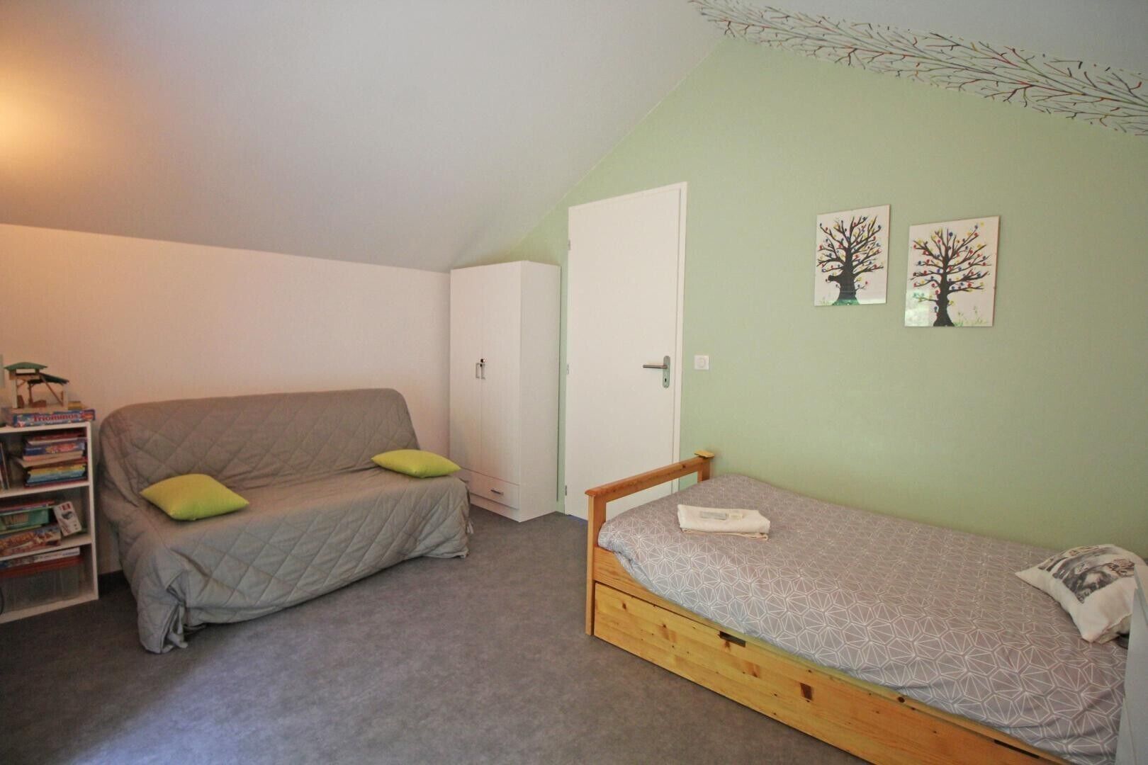 Un petit appartement d’une seule pièce comprenant un canapé, un lit, une armoire et une bibliothèque.