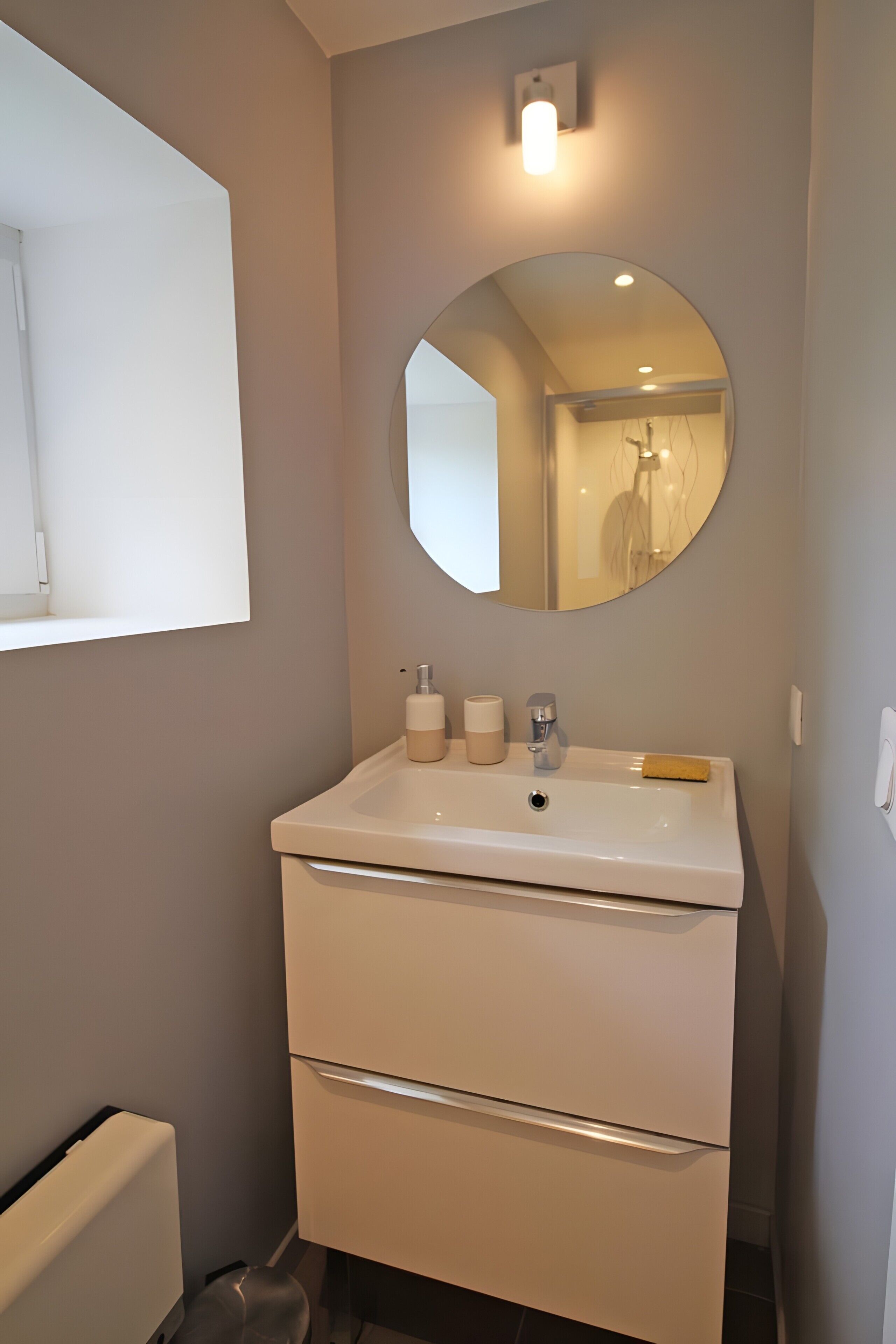 A bathroom with a white sink, mirror, and two drawers.