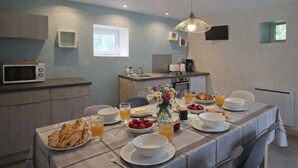 Un comedor con una mesa dispuesta para el desayuno, que incluye croissants, fruta y bebidas.