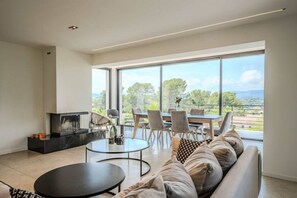 Ein modernes Wohnzimmer mit einer Couch, zwei runden Tischen und einem Essbereich mit Stühlen.