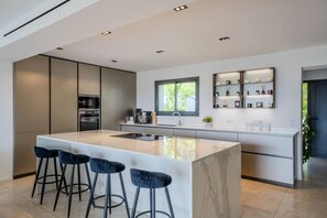 Eine moderne Küche mit einer zentralen Kochinsel, Barhocker, integrierten Geräten und einem Fenster.