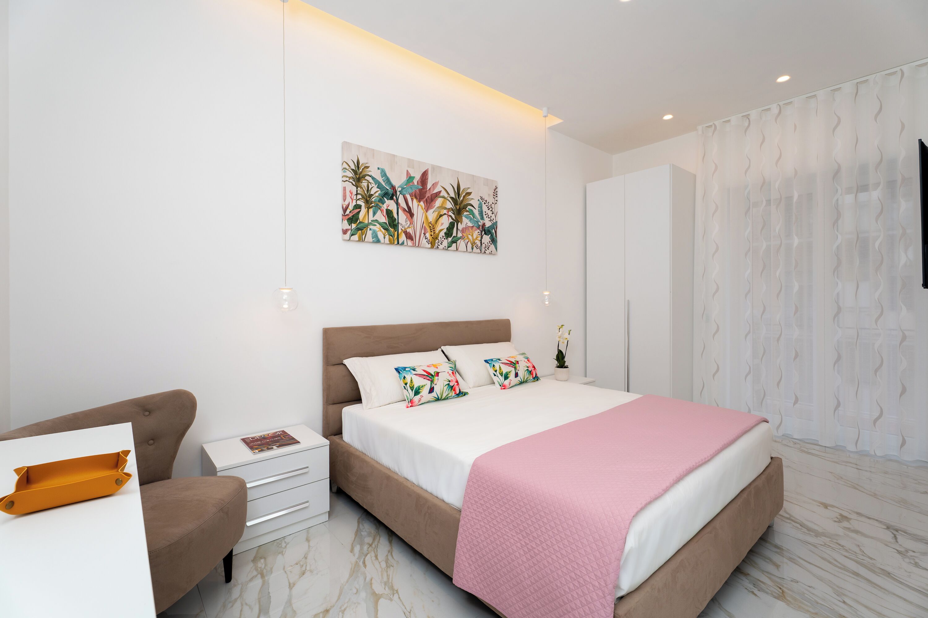Ein modernes Schlafzimmer mit einem großen Bett, einem Nachttisch, einem Sessel und einem Wandbild.