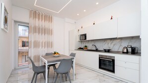 A modern kitchen with white cabinets, a marble countertop, and a built-in oven. - YourHome - Maremi Apartment (Piano di Sorrento)