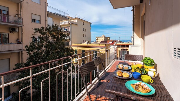 A balcony with a table set for breakfast, including plates of food, cups, and a plant. - YourHome - Maremi Apartment (Piano di Sorrento)
