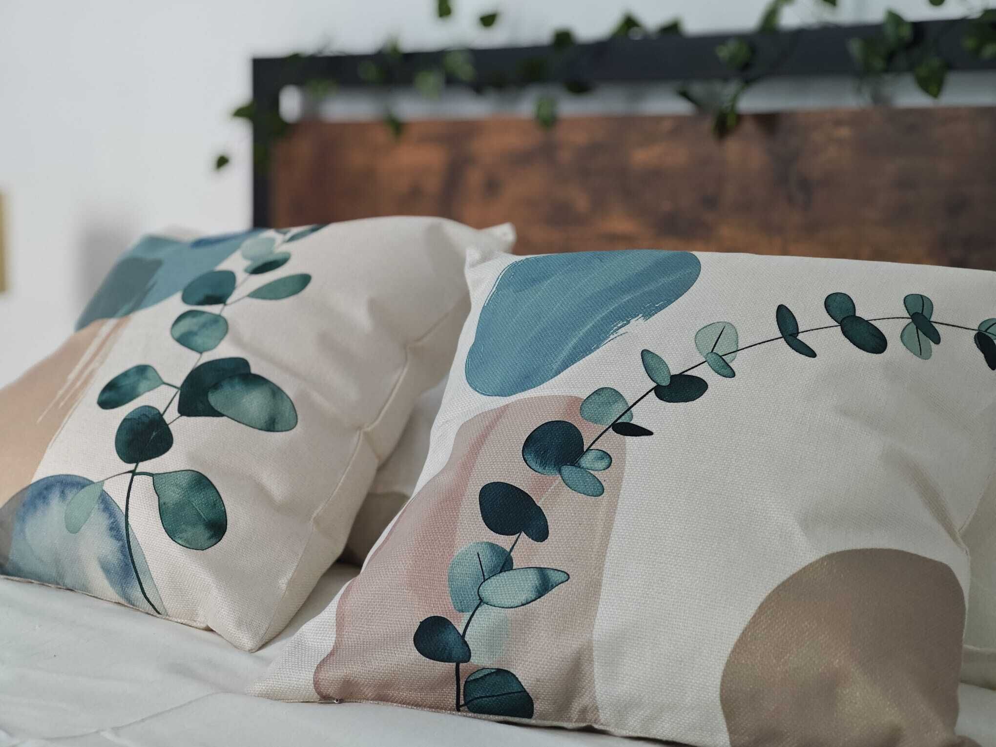 Cama con dos almohadas con diseño de hojas.