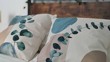 Cama con dos almohadas con diseño de hojas.