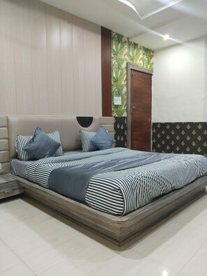 A bedroom with a bed, pillows, a wardrobe, and a wall with a leaf pattern. - HOTEL DYNA INN (Gwalior)