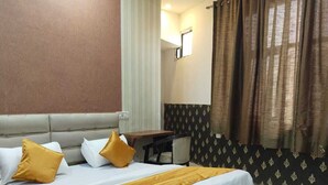 A hotel room with a large bed, a desk, and a window with curtains. - HOTEL DYNA INN (Gwalior)