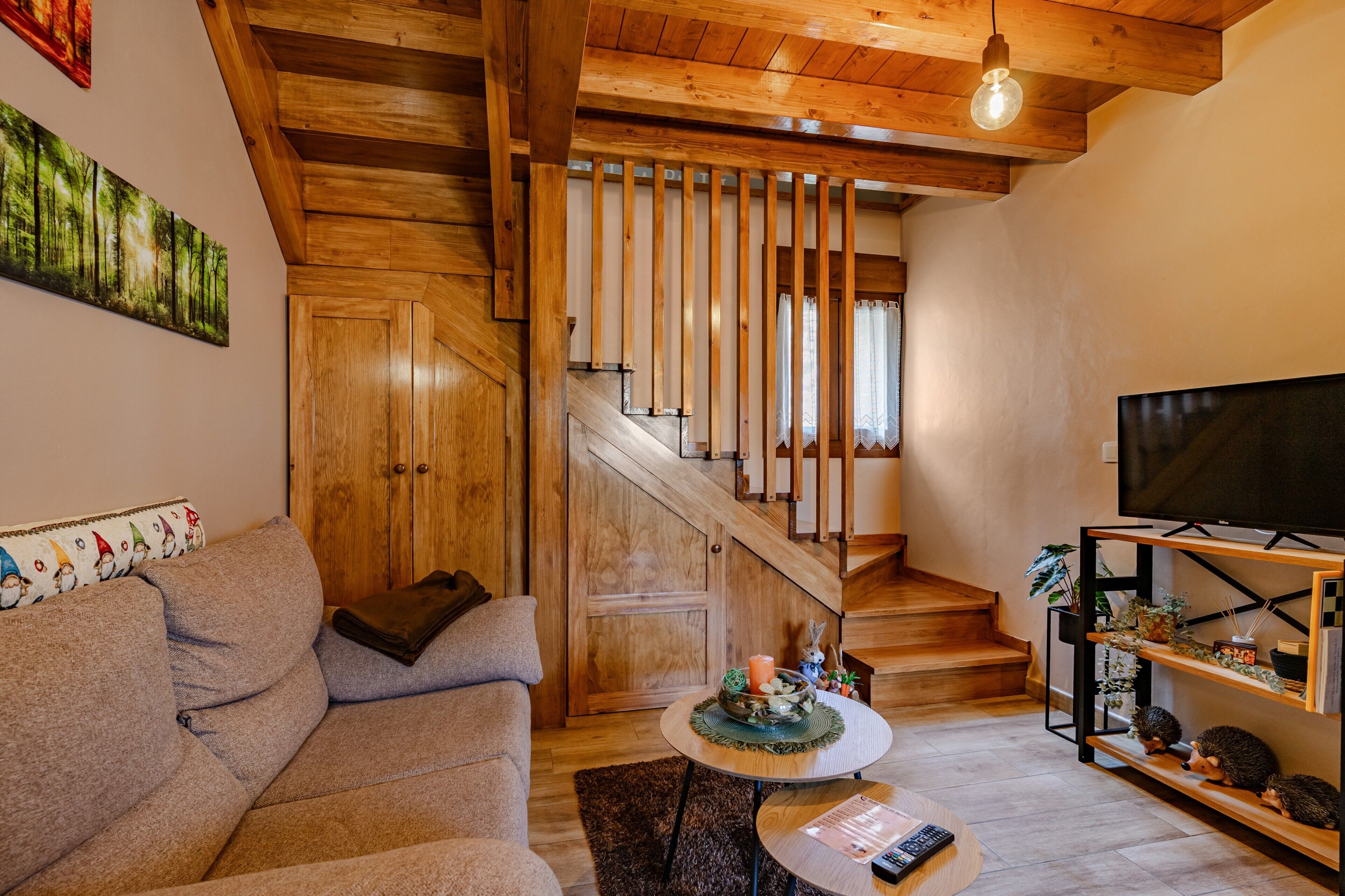 A living room with a sofa, a TV, a staircase, and a bookshelf.