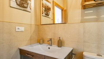 A bathroom with a white sink, wooden cabinet, and a toilet.