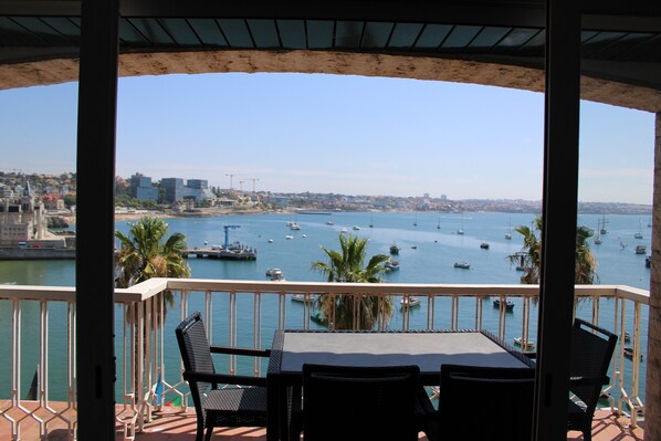 A balcony with a table and chairs overlooking a marina with boats and a cityscape. - Apartment 'Cascais Bay Terrace V' with Sea View, Wi-Fi and Air Conditioning (Cascais)