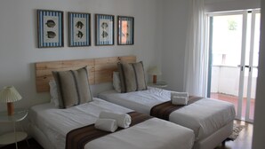 A hotel room with two beds, a wooden headboard, a small table with a lamp, and framed fish pictures on the wall. - Apartment 'Cascais Bay Terrace V' with Sea View, Wi-Fi and Air Conditioning (Cascais)