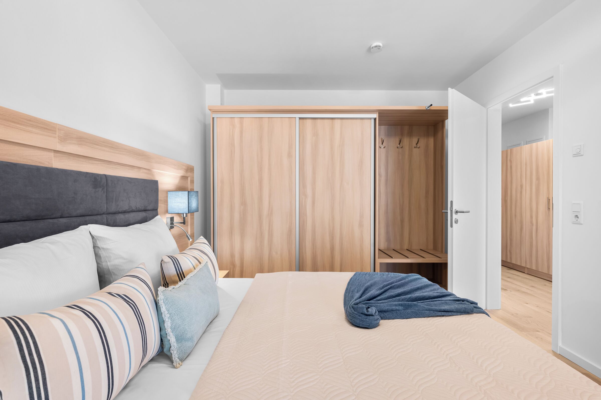 Ein modernes Schlafzimmer mit Bett, Nachttisch, Lampe und Kleiderschrank.