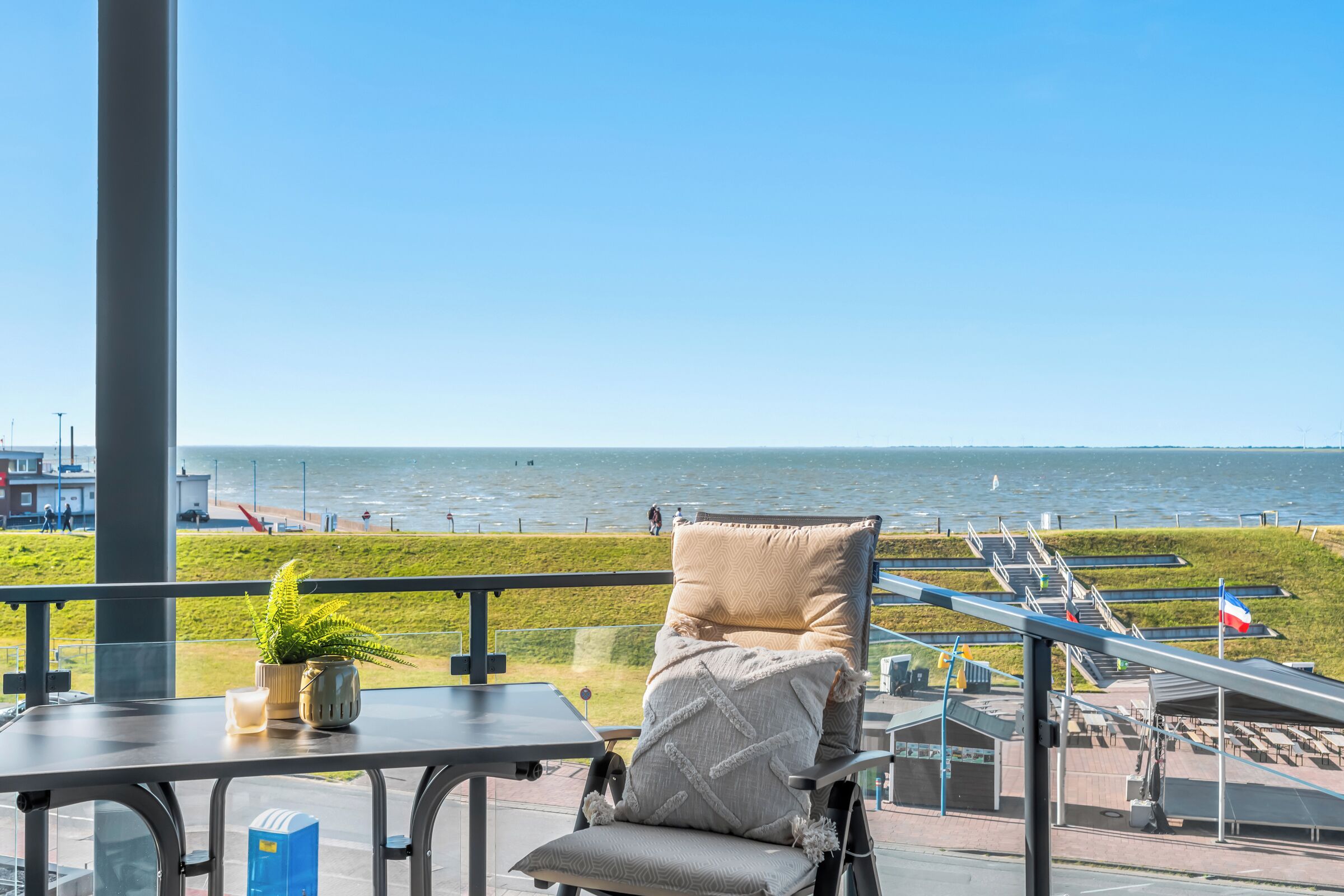 En balkon med havudsigt, en stol, et bord og en potteplante.