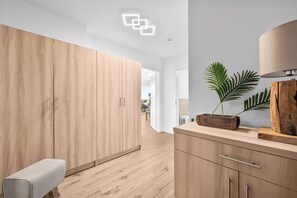 Et moderne interiør med trægulv, en bænk, et træskab og en plante.
