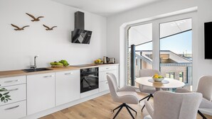 Eine moderne Küche mit Einbauofen, einem Essbereich mit rundem Tisch und Stühlen sowie einem großen Fenster mit Blick auf die Skyline.