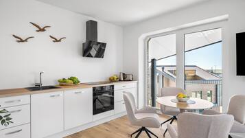 Una cucina moderna con forno integrato, un'area pranzo con tavolo e sedie rotonde, e un'ampia finestra che offre vista sulla città.