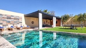 Piscina com espreguiçadeiras e área coberta com um mural.