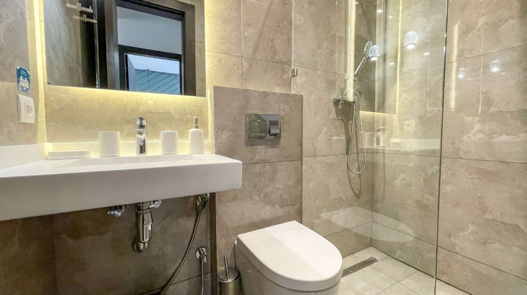 Un bagno moderno con lavandino bianco, WC e cabina doccia in vetro.