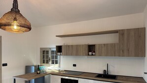 Une cuisine moderne dotée d’un plan de travail en bois, de meubles encastrés, d’un lave-vaisselle et d’un luminaire suspendu.