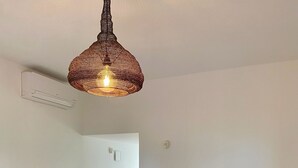 Un salon moderne avec un canapé gris, une table à manger agrémentée d’un panier en osier et un luminaire suspendu.