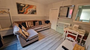 A living room with a sofa, a coffee table, a painting, a mirror, and a window. - The Red House, 2 Bed Garden Flat in Totterdown, Bristol BS3 4TJ near city centre (Bristol)