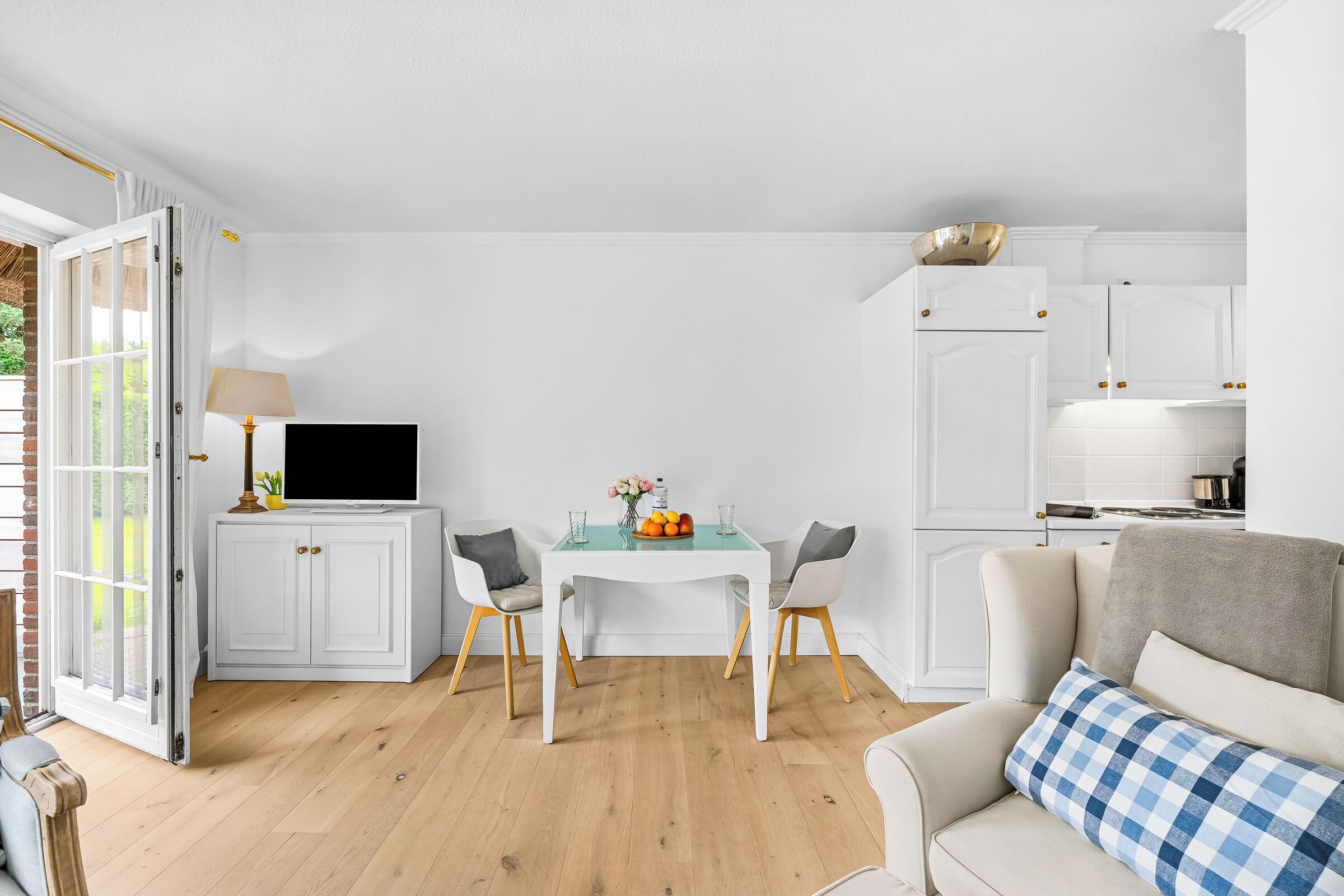 Ein Zimmer mit Esstisch, Stühlen, einer Couch und einem Fernseher auf einem Schrank.