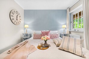 Une chambre à coucher avec un lit, une horloge, une fenêtre et une table de chevet avec une lampe.
