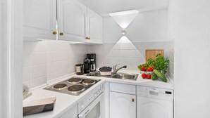 A modern kitchen with white cabinetry, a built-in stove, a dishwasher, and a sink.