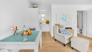 A modern living room with a glass-top dining table, a sofa, and a coffee table.