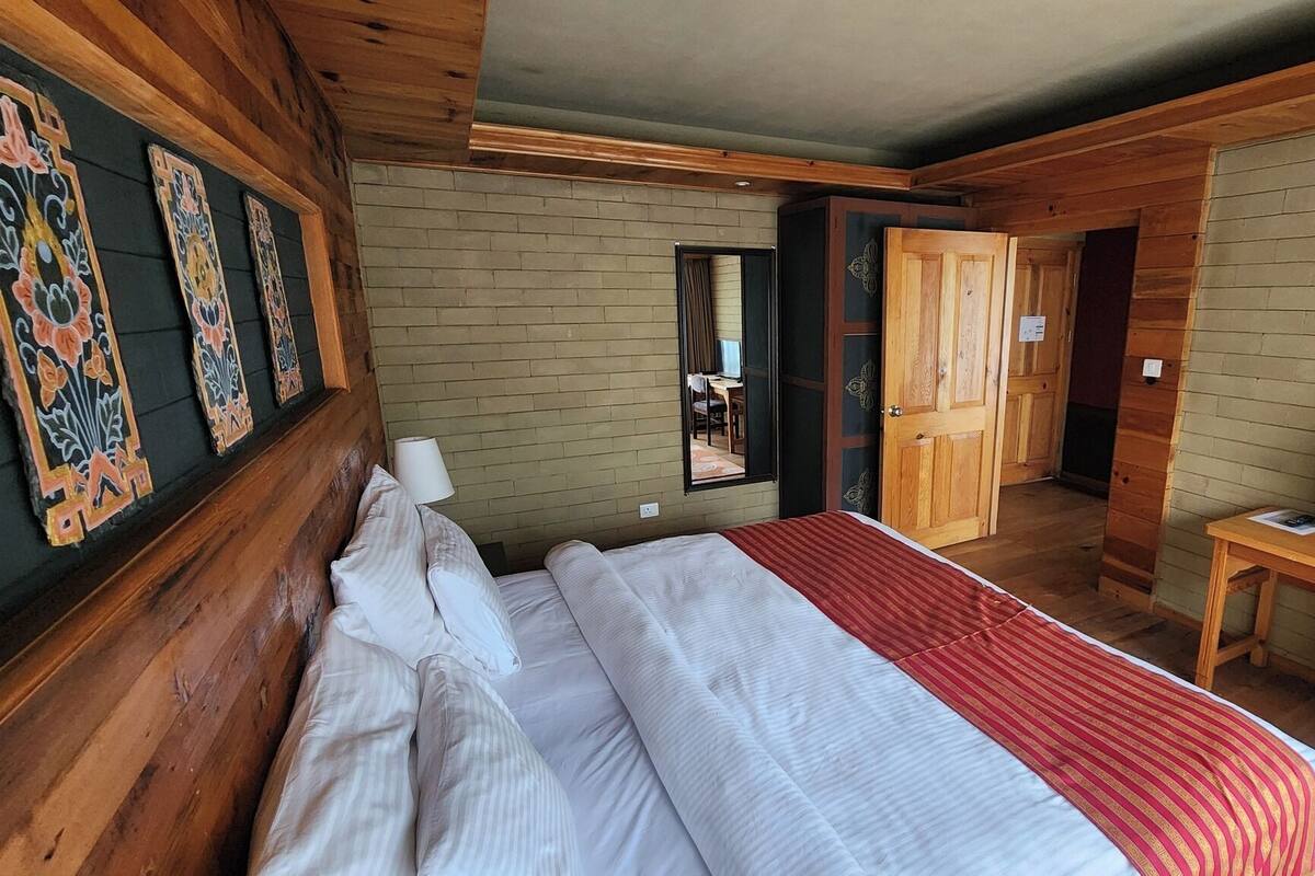 A wooden cabin-style room with a bed, a desk, and a TV.