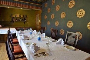 A dining area with a long table set for a meal, chairs, and a wall with decorative plates. - Hotel Valley Thimphu (Thimphu)