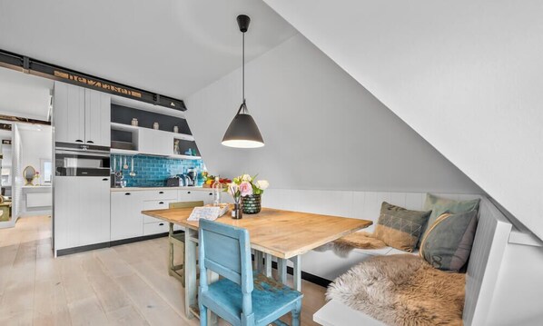 A modern kitchen with white cabinets, a blue backsplash, and a wooden dining table. - Luxury vacation apartment in List on Sylt near the beach, with a sauna and parking (List auf Sylt)