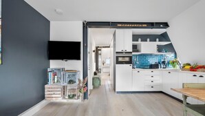 A modern kitchen with white cabinets, a blue backsplash, and a wooden dining table. - High-quality vacation apartment in List on Sylt by the beach, with sauna and parking space (List auf Sylt)