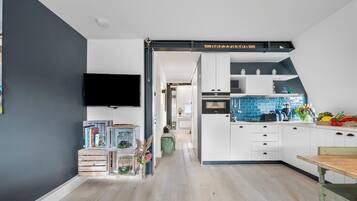 Een moderne keuken met witte kastjes, een blauwe achterwand en een houten eettafel.